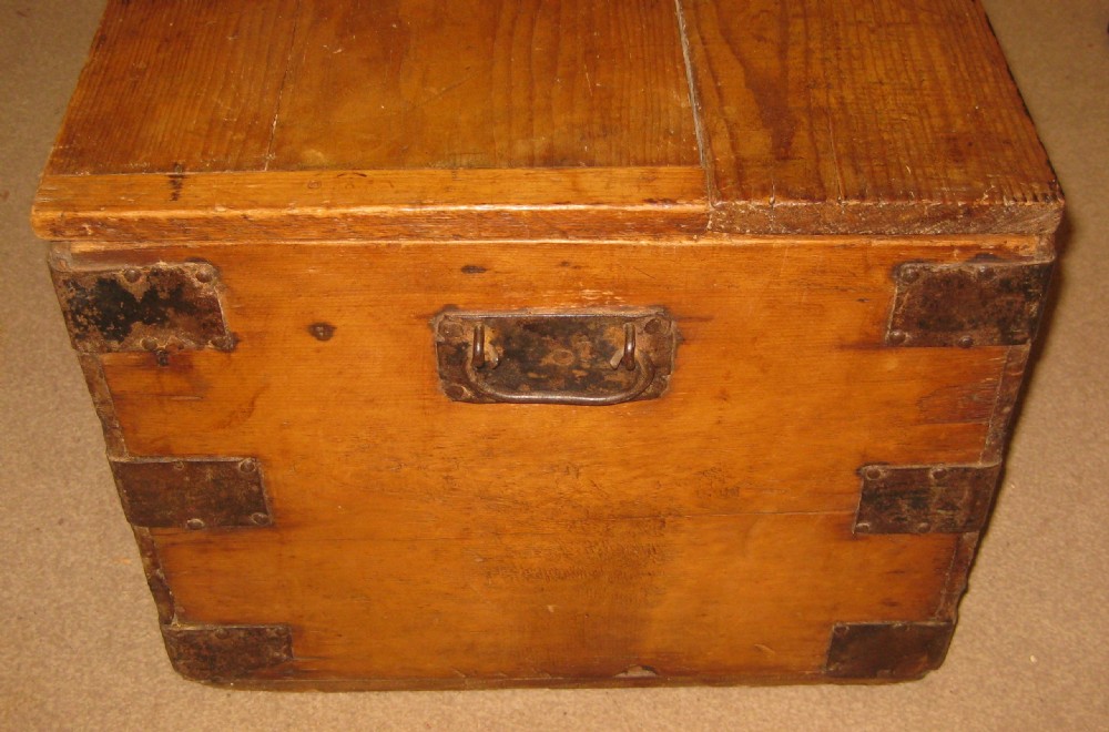 A rectangular solid pine storage trunk featuring iron corner brackets and a central metal lock mechanism with key. View VI