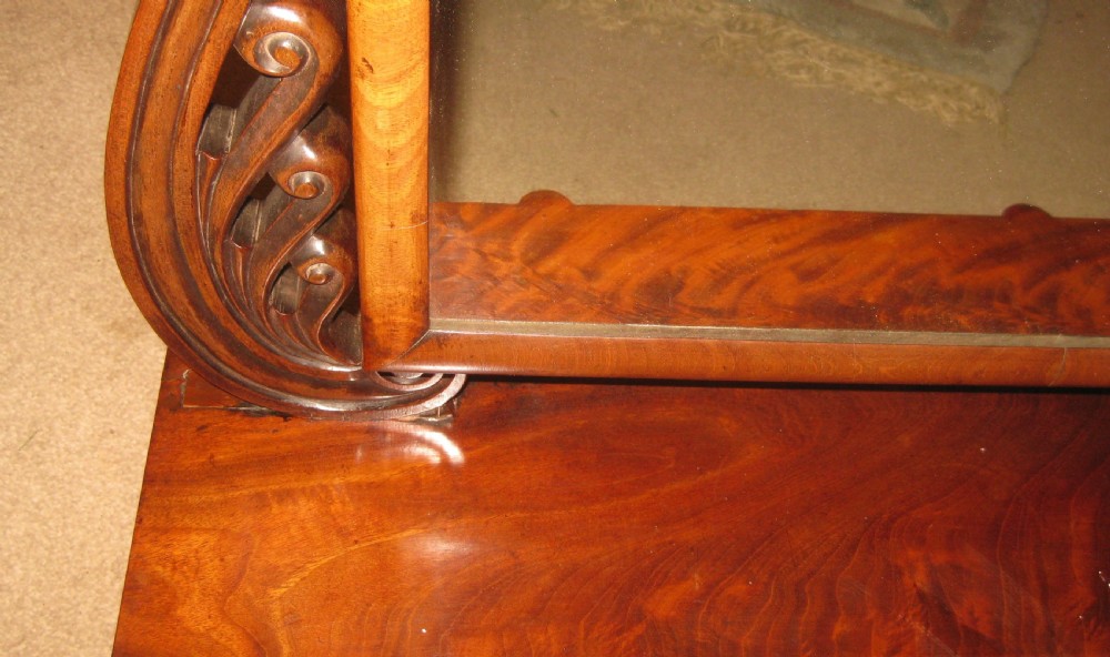 A Victorian flame mahogany swing dressing mirror featuring carved scroll upright supports and a rectangular tilting glass resting on a base with drawers. View III