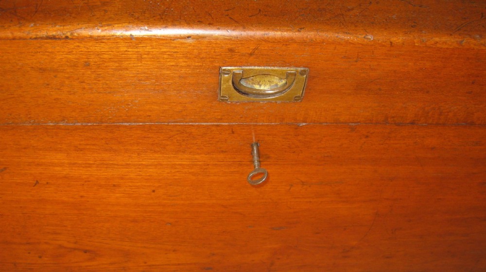 A rectangular Victorian solid teak wooden trunk featuring a hinged top lid, a central flush brass catch, and a keyhole on the front panel. View IV