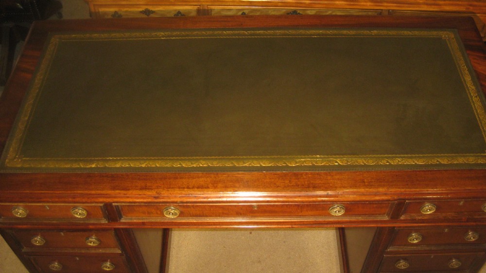 A Victorian mahogany pedestal desk featuring a dark green leather writing surface with gold tooling, multiple drawers with round brass handles, and solid plinth bases. View III