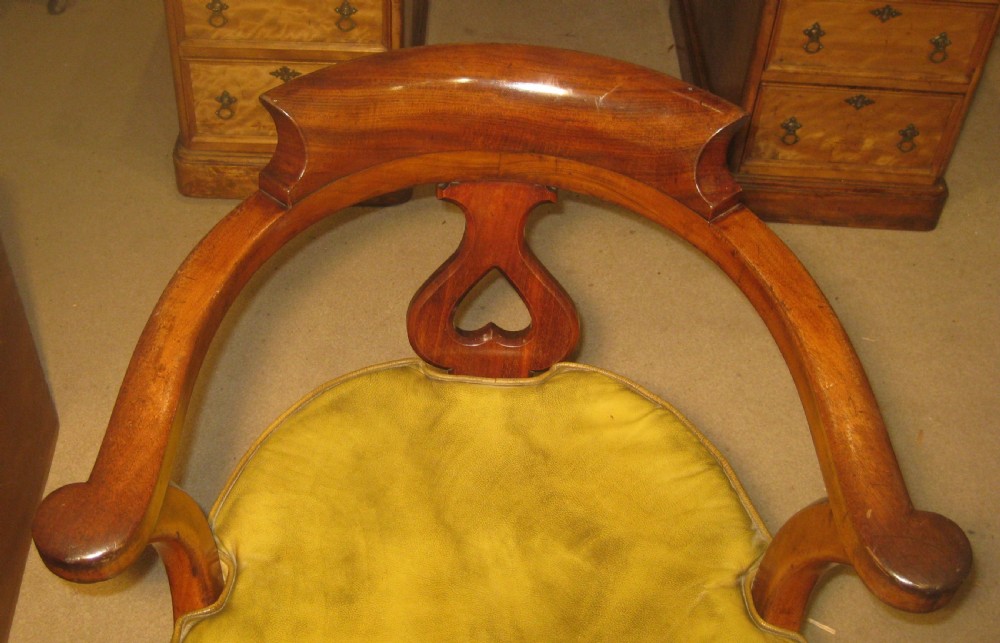 A Victorian mahogany Captains desk chair featuring a curved crest rail, pierced back splat, patinated leather seat, and turned front legs. View II