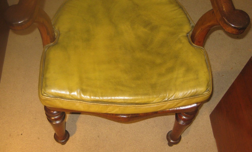 A Victorian mahogany Captains desk chair featuring a curved crest rail, pierced back splat, patinated leather seat, and turned front legs. View III