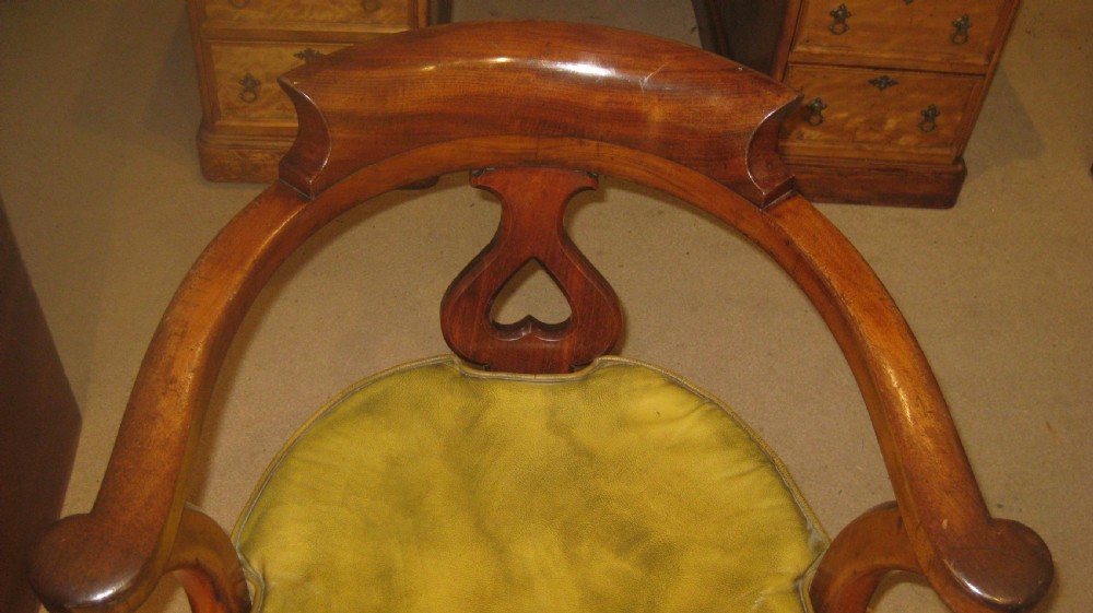 A Victorian mahogany Captains desk chair featuring a curved crest rail, pierced back splat, patinated leather seat, and turned front legs. View IV