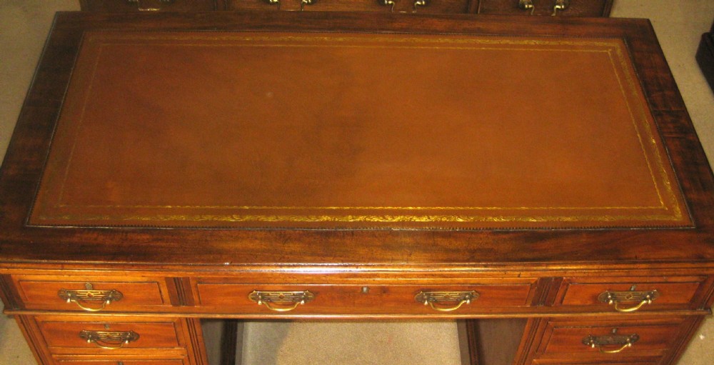 Victorian mahogany pedestal desk featuring a gold-tooled brown leather writing surface, brass handles, and two drawer pedestals on plinth bases. View III