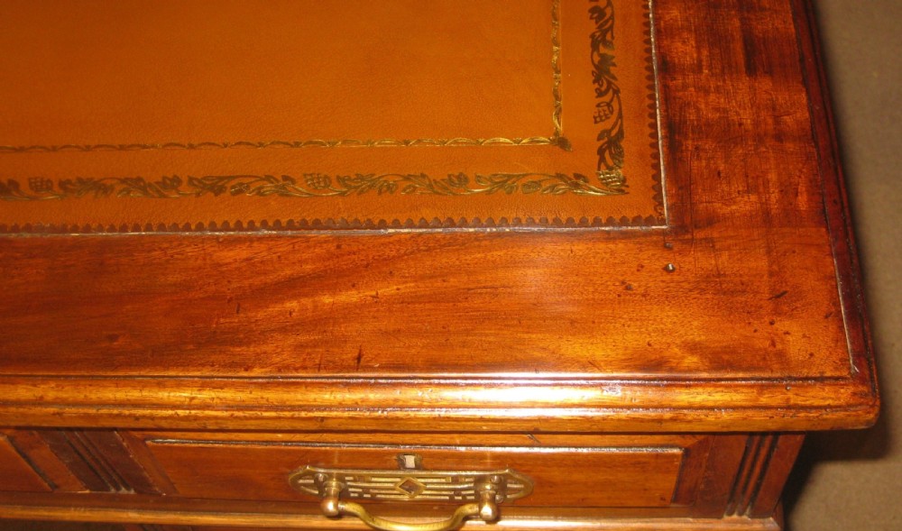 Victorian mahogany pedestal desk featuring a gold-tooled brown leather writing surface, brass handles, and two drawer pedestals on plinth bases. View VIII