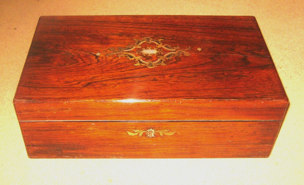 A rectangular Victorian rosewood writing slope featuring a figured grain finish with a central foliate inlay on the lid and an inlaid escutcheon on the front.