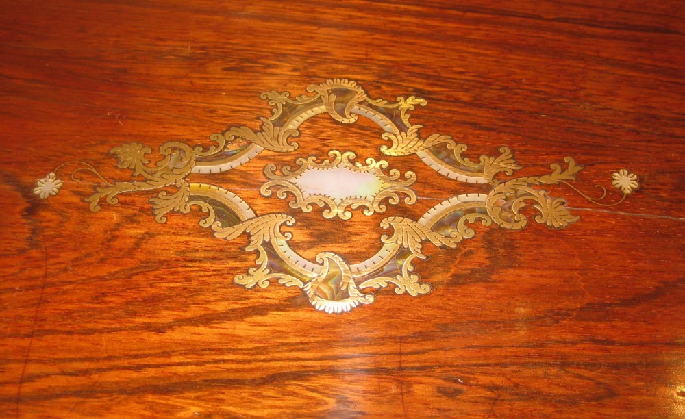 A rectangular Victorian rosewood writing slope featuring a figured grain finish with a central foliate inlay on the lid and an inlaid escutcheon on the front. View II