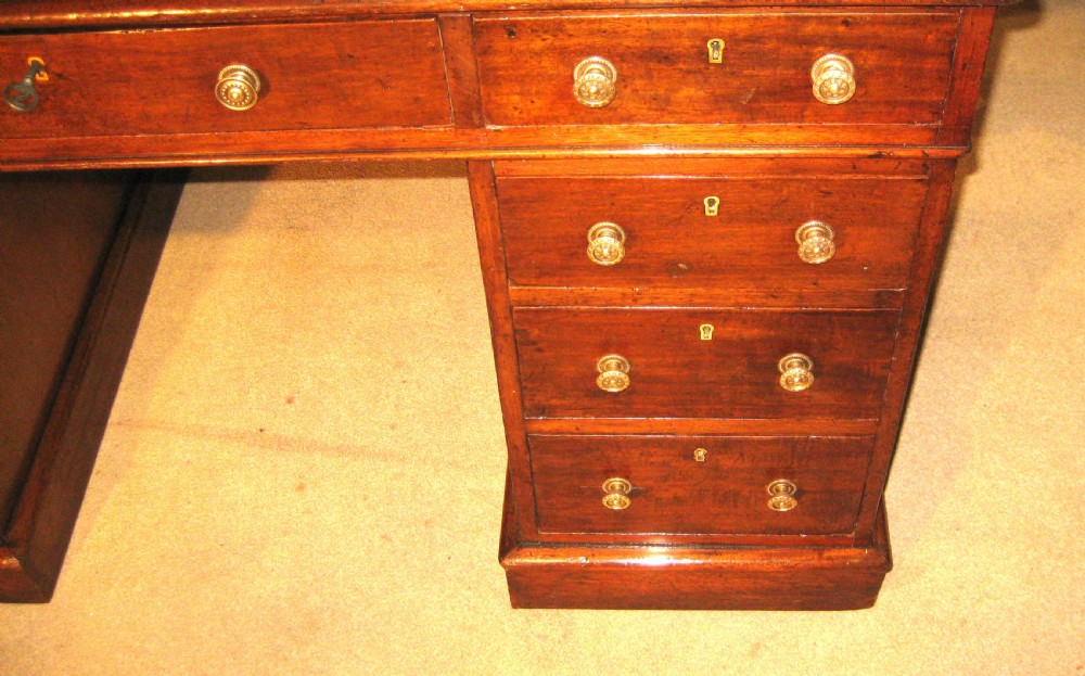 A Victorian mahogany pedestal desk featuring a green leather writing surface insert and nine storage drawers with brass knobs. View III