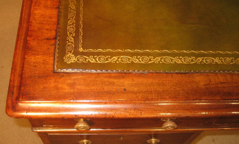 A Victorian mahogany pedestal desk featuring a green leather writing surface insert and nine storage drawers with brass knobs. View IX