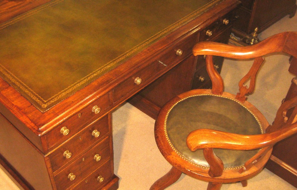 A Victorian mahogany pedestal desk featuring a green leather writing surface insert and nine storage drawers with brass knobs. View XII