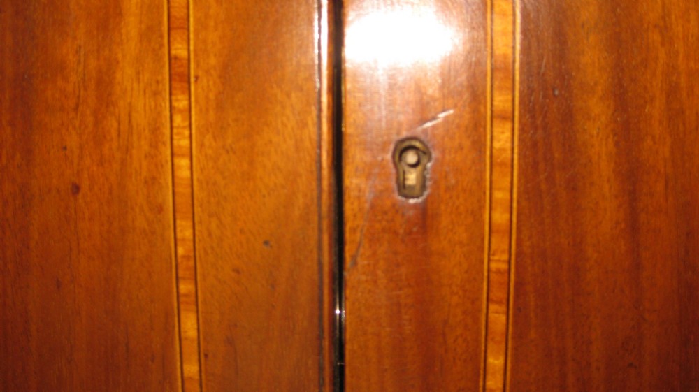 A late Victorian mahogany stationery cabinet featuring inlaid satinwood border detailing on double panelled doors and a central brass keyhole escutcheon. View VIII