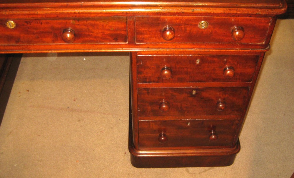 A Victorian mahogany pedestal desk featuring nine drawers with turned handles, rounded corners, and a green leather insert. View III