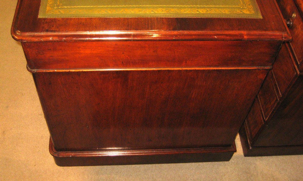 A Victorian mahogany pedestal desk featuring nine drawers with turned handles, rounded corners, and a green leather insert. View VII