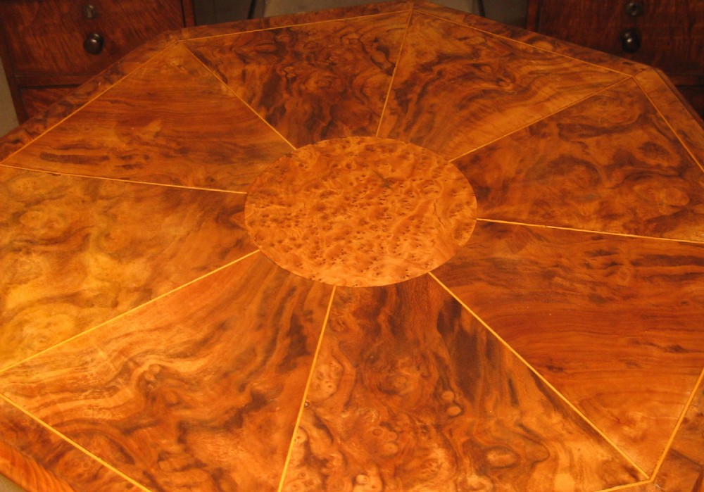 An octagonal burr walnut occasional table with segmentally veneered top resting on a carved central column and tripod legs with castors. View III