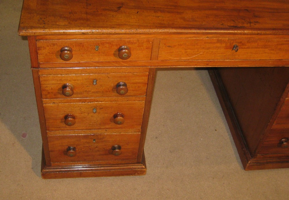 A Victorian golden mahogany pedestal desk featuring nine drawers with turned wooden knobs around a central kneehole. View II