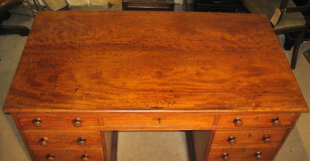 A Victorian golden mahogany pedestal desk featuring nine drawers with turned wooden knobs around a central kneehole. View IV