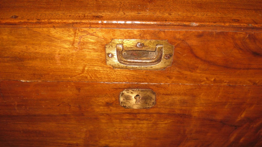A rectangular solid camphorwood campaign trunk featuring visible wood grain, corner brass brackets, and a flush inset brass handle. View V
