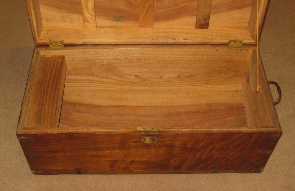 A rectangular solid camphorwood campaign trunk featuring visible wood grain, corner brass brackets, and a flush inset brass handle. View IX