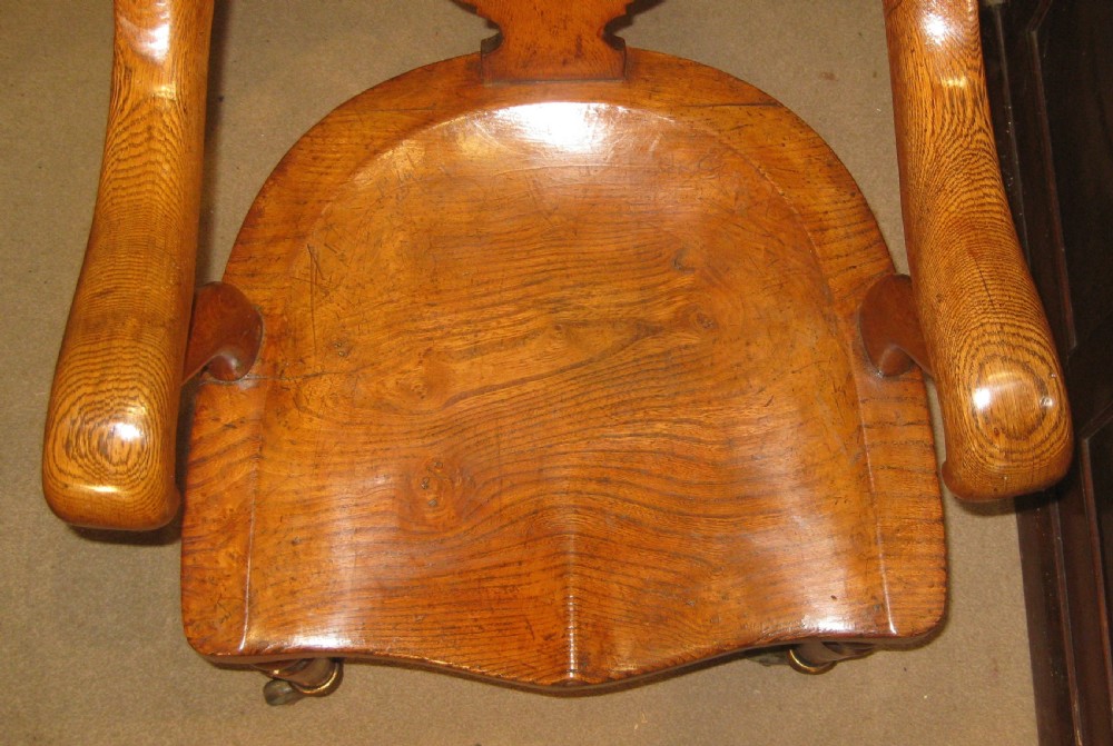 Victorian golden oak desk chair with a curved backrest, carved central splat, green leather padded seat, and turned front legs on brass castors. View III