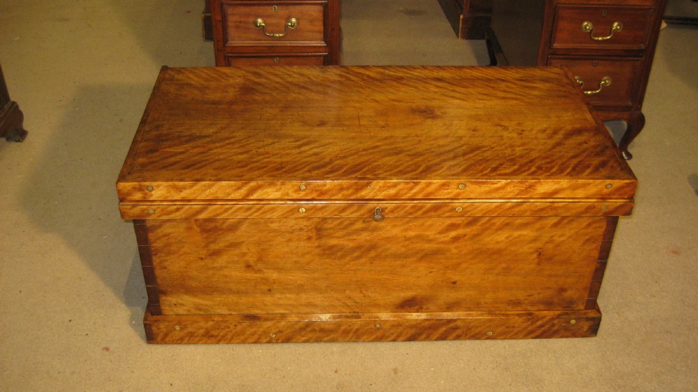 A rectangular Victorian solid satinwood storage trunk featuring prominent rippled timber grain, brass fixings along the lid, and a central keyhole. View II