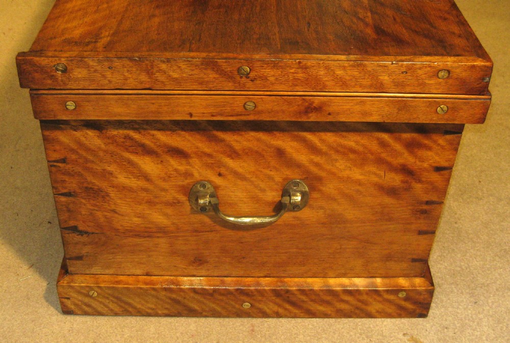 A rectangular Victorian solid satinwood storage trunk featuring prominent rippled timber grain, brass fixings along the lid, and a central keyhole. View V