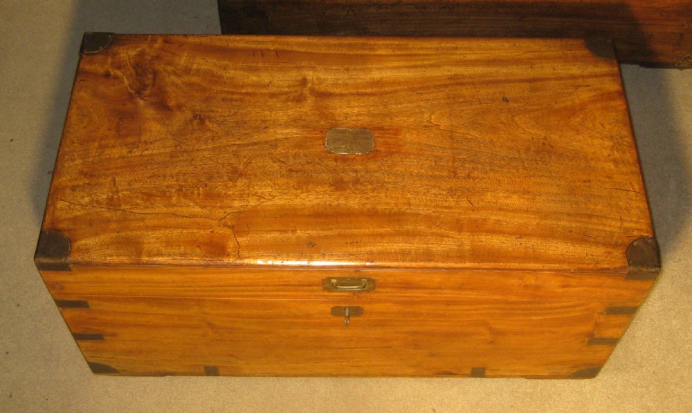 A Victorian warm brown camphorwood campaign trunk with flush brass corner straps, central lid plaque, and keyhole escutcheon. View II