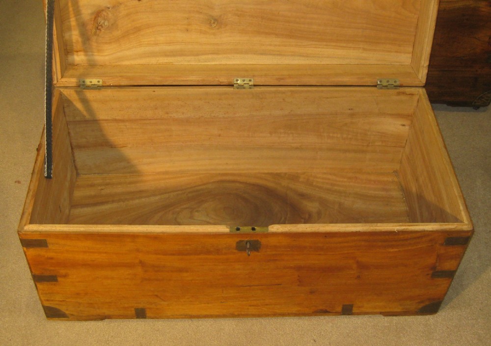 A Victorian warm brown camphorwood campaign trunk with flush brass corner straps, central lid plaque, and keyhole escutcheon. View IV