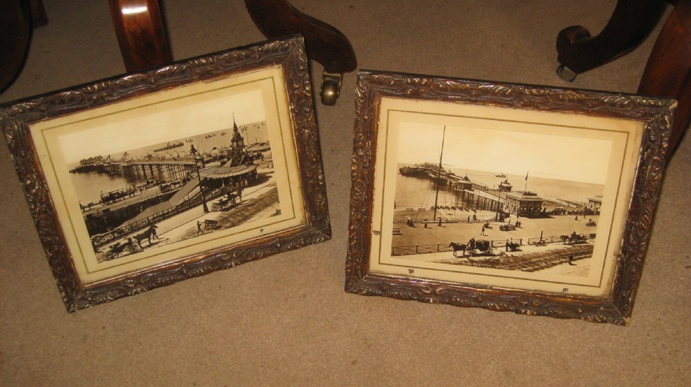 A pair of matching dark carved wooden frames containing sepia-toned historical photographs of the pier and seafront at Brighton.