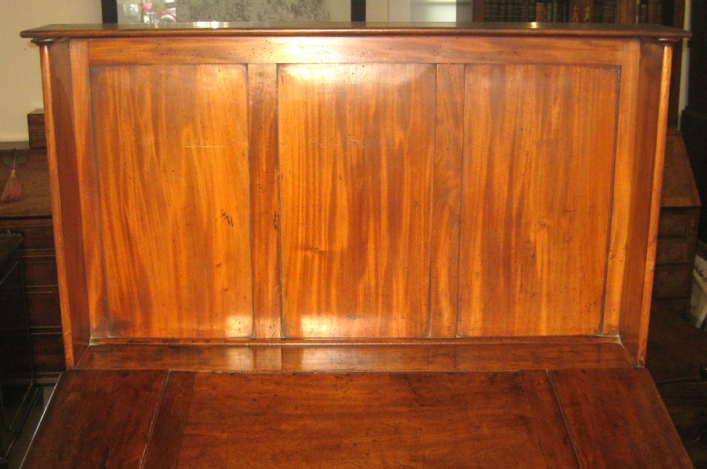 An early Victorian golden mahogany clerks desk featuring a sloped lid, upper gallery panel, two small drawers, gothic quatrefoil frieze, and turned legs. View III