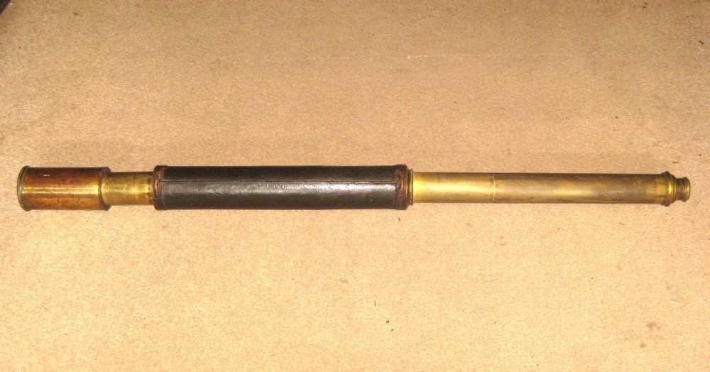 An antique brass marine telescope with an extending draw tube and a central dark leather-bound barrel.