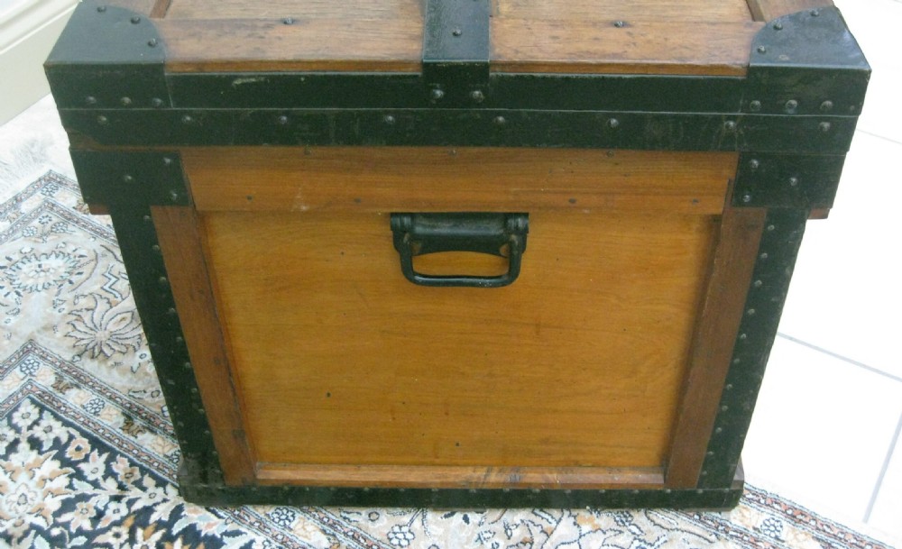 A rectangular wooden sea chest featuring black metal corner brackets, metal edge binding, and twin oval keyhole escutcheons. View V