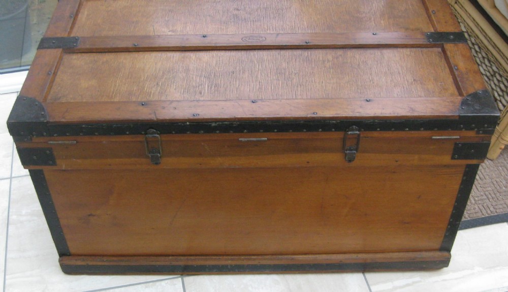 A rectangular wooden sea chest featuring black metal corner brackets, metal edge binding, and twin oval keyhole escutcheons. View VI