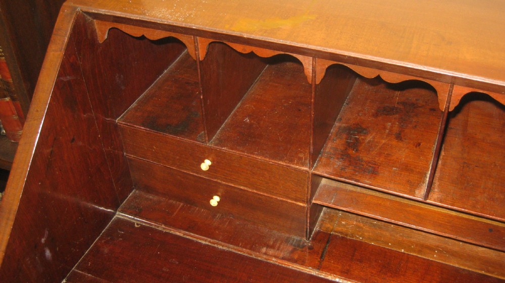 An antique Georgian mahogany bureau featuring a sloping fall-front lid above four graduated long drawers with brass handles and bracket feet. View III