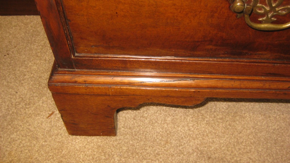 An antique Georgian mahogany bureau featuring a sloping fall-front lid above four graduated long drawers with brass handles and bracket feet. View VI