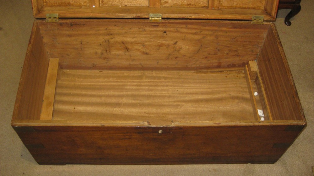 A rectangular Victorian solid camphorwood campaign trunk featuring flush brass corner straps, a brass carrying handle, and a keyhole escutcheon. View VI