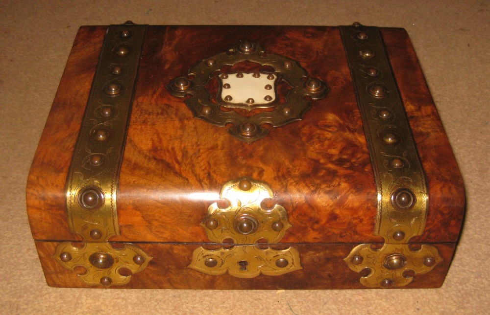 A mid-Victorian burr walnut jewellery box featuring engraved brass strapwork, studding, and a central inlaid plaque.