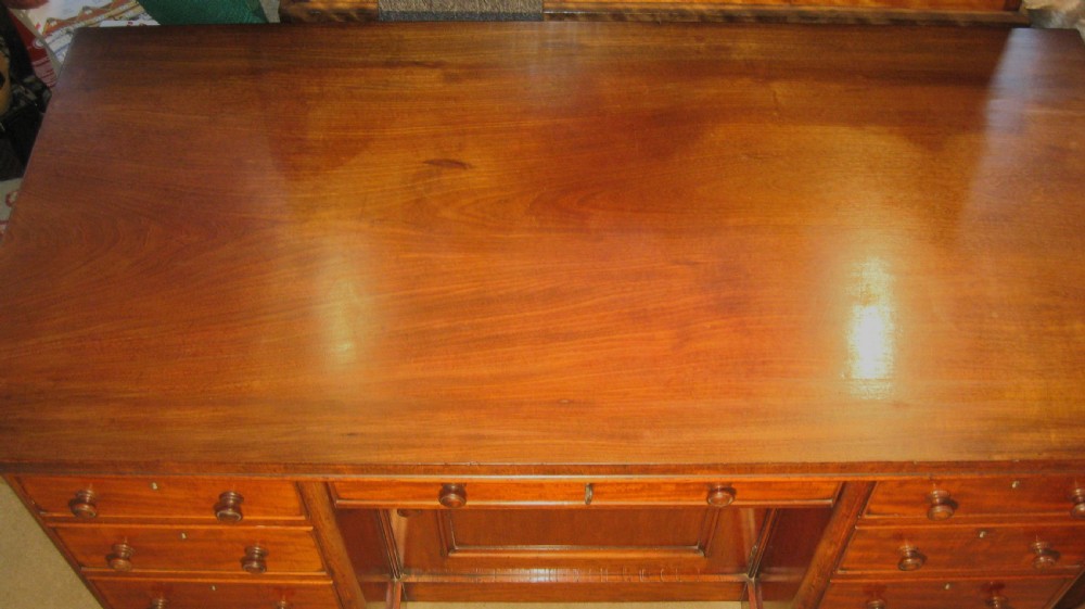 Victorian flame mahogany kneehole desk featuring multiple side drawers with turned wooden knobs and a central recessed cupboard on a plinth base. View IV