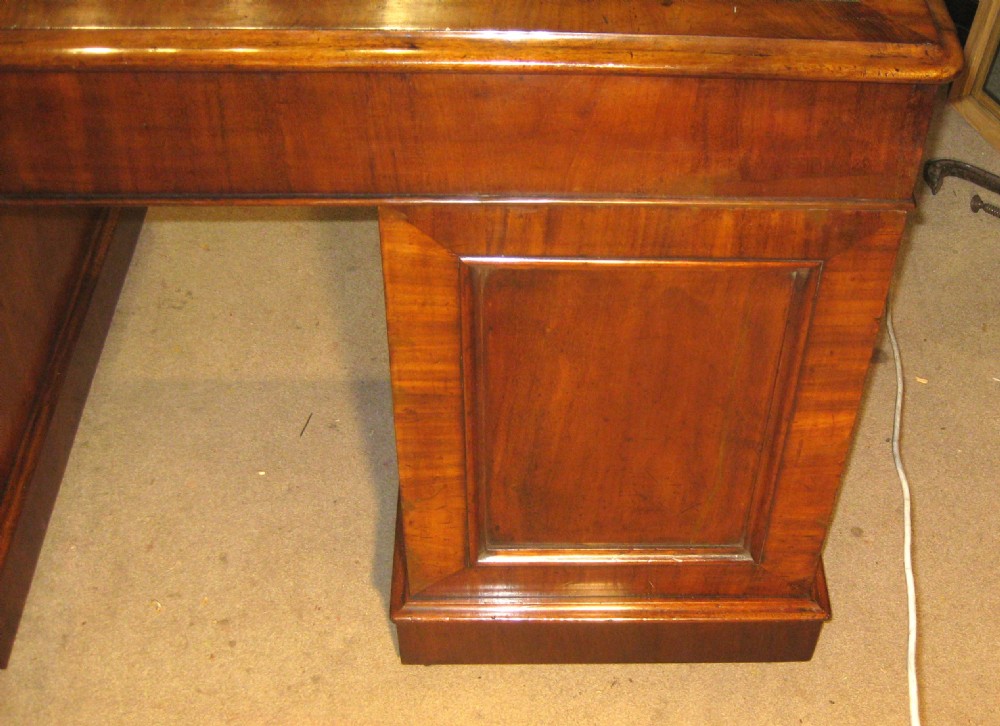 A Victorian mahogany pedestal desk featuring a green leather inset writing surface, nine drawers with turned wooden knobs, and a plinth base. View VIII