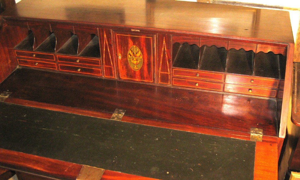 A Georgian mahogany fall-front bureau desk with crossbanded inlay, brass swan-neck handles, multiple drawers, and bracket feet. View V