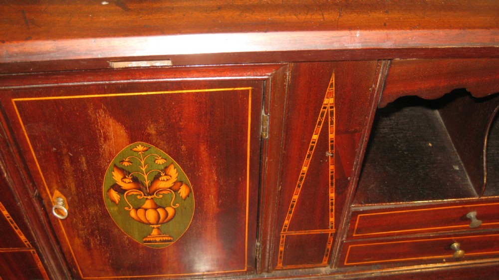 A Georgian mahogany fall-front bureau desk with crossbanded inlay, brass swan-neck handles, multiple drawers, and bracket feet. View VI