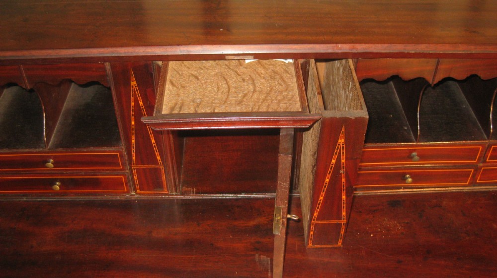 A Georgian mahogany fall-front bureau desk with crossbanded inlay, brass swan-neck handles, multiple drawers, and bracket feet. View VII