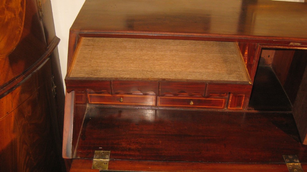 A Georgian mahogany fall-front bureau desk with crossbanded inlay, brass swan-neck handles, multiple drawers, and bracket feet. View VIII