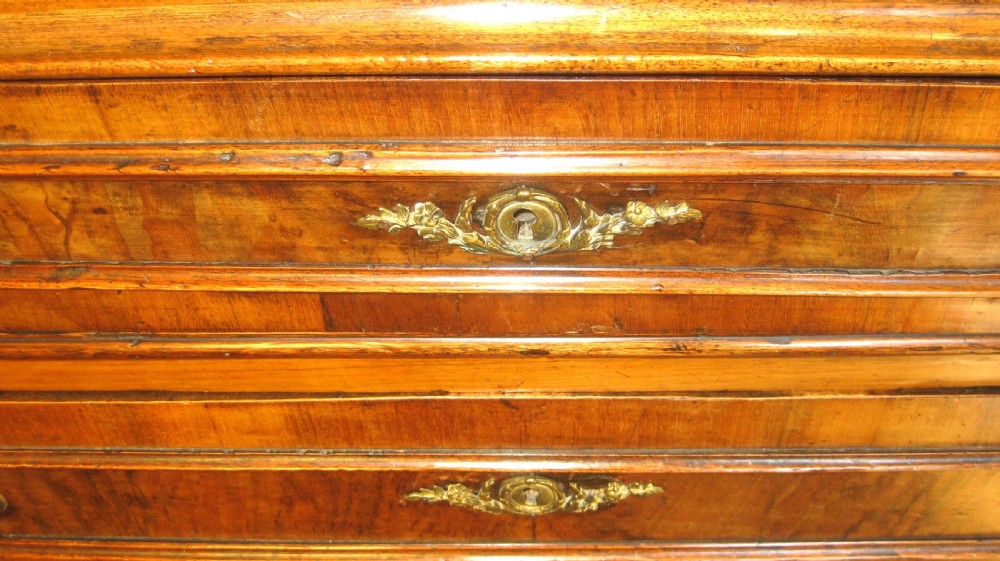 A Victorian walnut chest of drawers featuring four graduated drawers with moulded surrounds, brass keyhole escutcheons, small brass knobs, and bun feet. View II