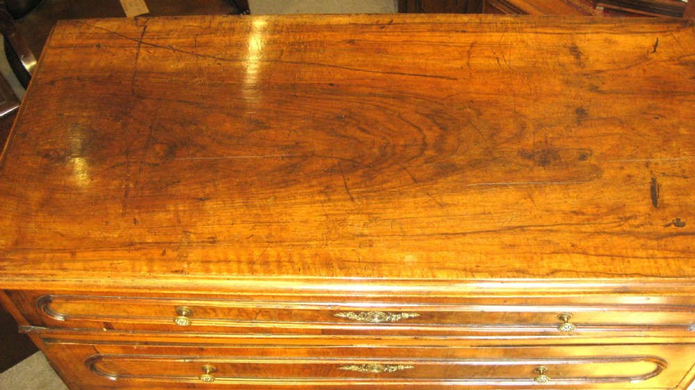 A Victorian walnut chest of drawers featuring four graduated drawers with moulded surrounds, brass keyhole escutcheons, small brass knobs, and bun feet. View III