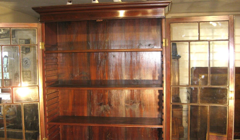 A tall nineteenth-century mahogany bookcase cabinet featuring glazed upper doors with geometric glazing bars above double flame mahogany lower cupboard doors. View VI