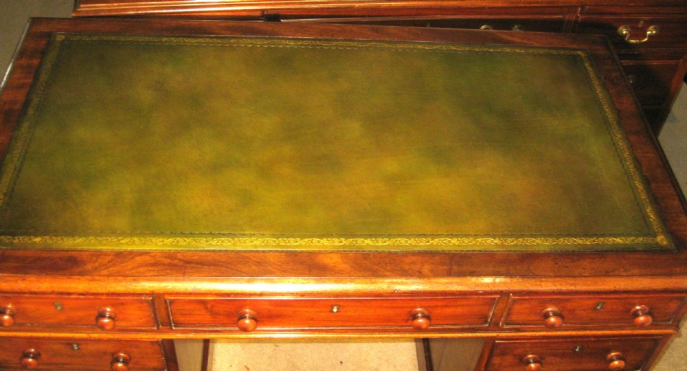 A late Victorian mahogany pedestal desk featuring a dark green gilt-tooled leather writing surface, multiple drawers with turned wooden knob handles, and twin pedestals on plinth bases. View III