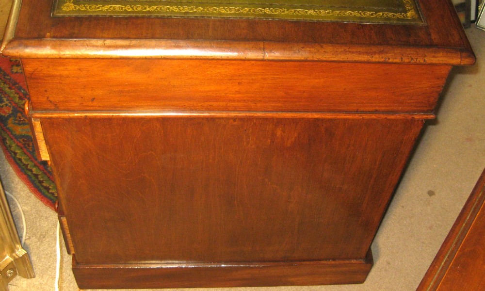 A late Victorian mahogany pedestal desk featuring a dark green gilt-tooled leather writing surface, multiple drawers with turned wooden knob handles, and twin pedestals on plinth bases. View VI
