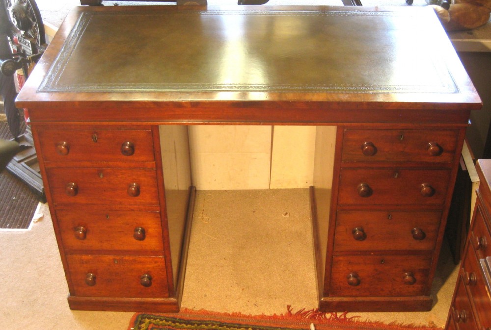 A Victorian mahogany pedestal desk featuring a dark green leather writing surface and twin pedestals fitted with wooden knob handles.