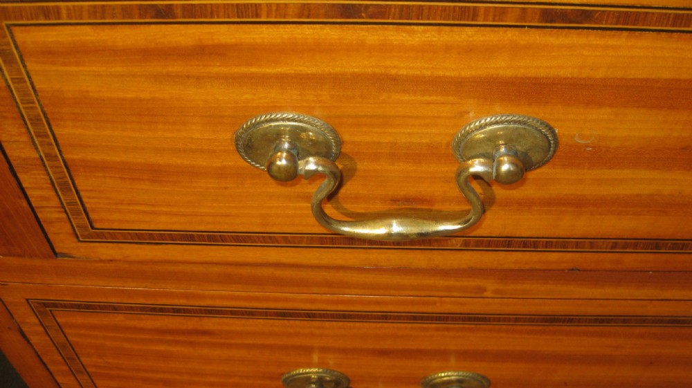 An Edwardian satinwood bureau bookcase featuring a two-door astragal glazed upper display section above a fall-front desk and three long drawers with brass handles. View VI