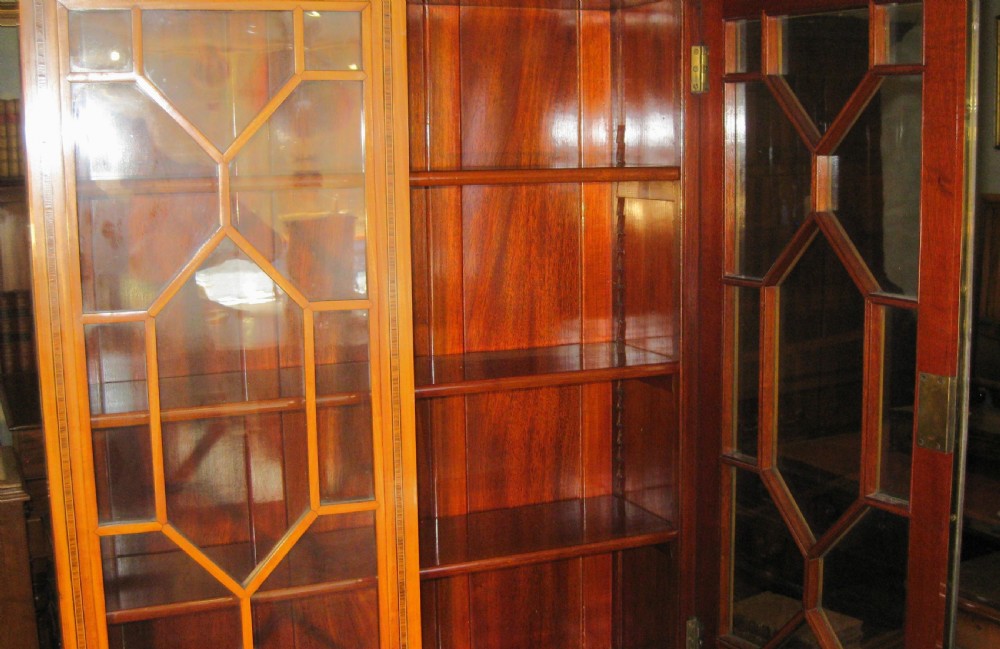 An Edwardian satinwood bureau bookcase featuring a two-door astragal glazed upper display section above a fall-front desk and three long drawers with brass handles. View X
